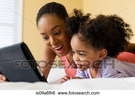 Mother and daughter using digital tablet View Large Photo Image Stock Photograph - Mother and daughter using digital tablet. Fotosearch