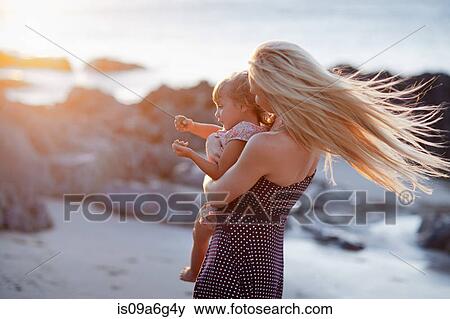 Stock Photo - Mother holding daughter on beach. Fotosearch