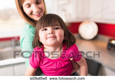 Stock Photograph - Mother holding female toddler daughter to look at camera. Fotosearch