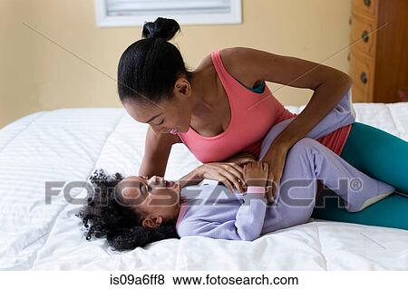 Mother tickling daughter on bed View Large Photo Image Stock Photo - Mother tickling daughter on bed. Fotosearch