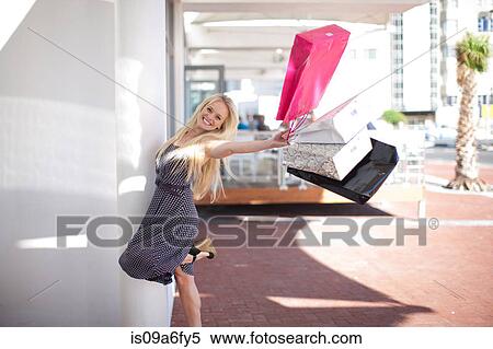 Stock Photography - One happy young women swinging shopping bags. Fotosearch