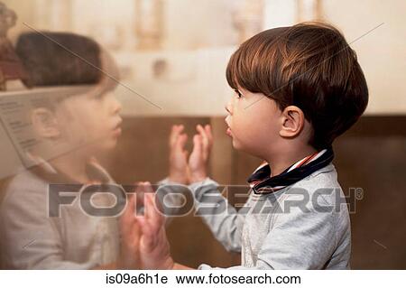 Stock Image - Portrait of male toddler looking at his reflection. Fotosearch