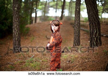 Stock Image - Portrait of male toddler wearing tiger suit alone in woods. Fotosearch