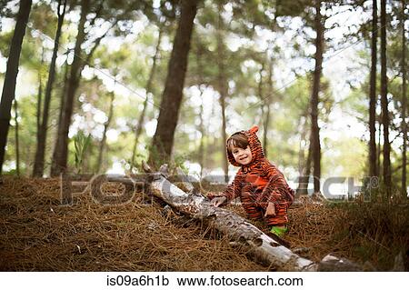 Stock Image - Portrait of male toddler wearing tiger suit playing in woods. Fotosearch