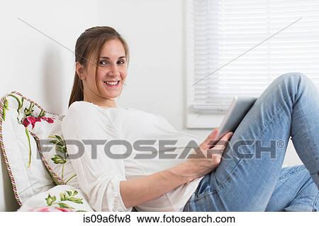 Stock Photo - Portrait of pregnant woman on bed holding digital tablet. Fotosearch