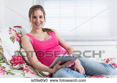 Portrait of pregnant woman resting on bed with digital tablet View Large Photo Image Stock Image - Portrait of pregnant woman resting on bed with digital tablet. Fotosearch