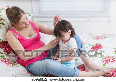 Pregnant woman and toddler daughter on bed looking at smartphone View Large Photo Image Stock Image - Pregnant woman and toddler daughter on bed looking at smartphone. Fotosearch