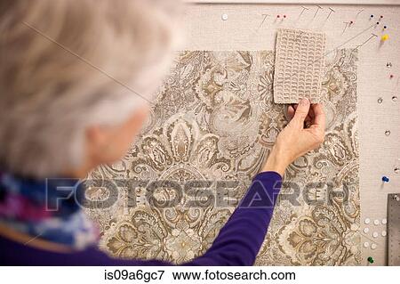 Stock Photo - Senior woman choosing textile swatches. Fotosearch