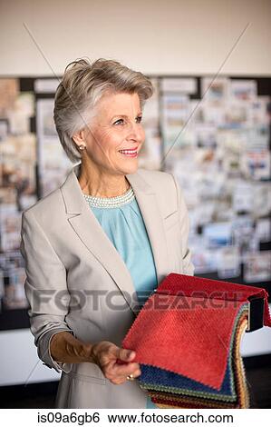 Stock Photograph - Senior woman holding textile swatch. Fotosearch