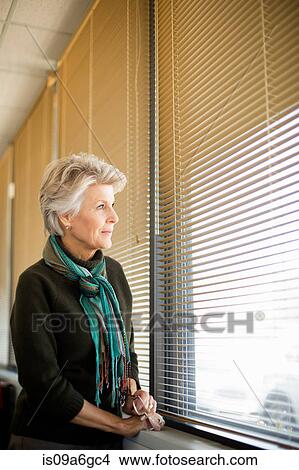 Senior woman looking through window View Large Photo Image Picture - Senior woman looking through window. Fotosearch