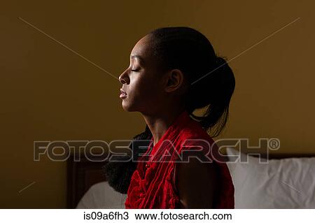 Stock Image - Side view of young woman with eyes closed. Fotosearch