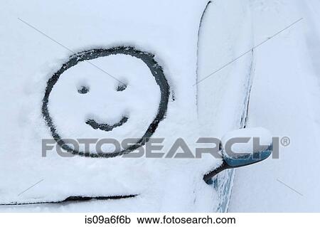 Stock Image - Smiley face drawn in snow on car windscreen. Fotosearch