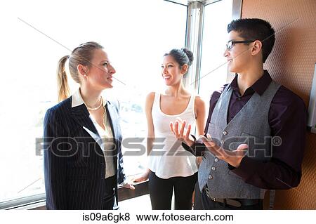 Stock Photo - Three young businesspeople talking. Fotosearch