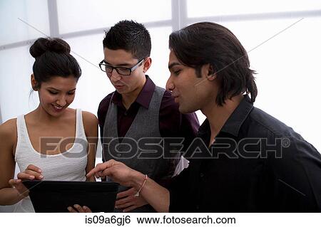 Stock Photograph - Three young businesspeople using digital tablet. Fotosearch