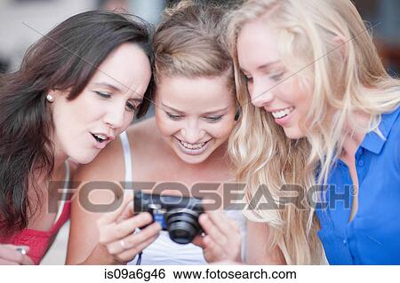 Stock Photograph - Three young women looking at photos. Fotosearch