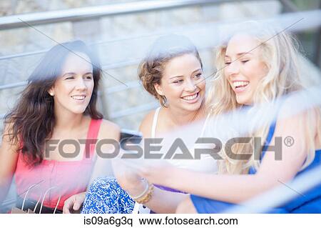 Stock Photography - Three young women looking at photos. Fotosearch