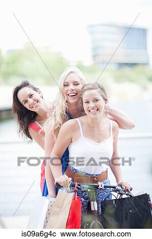 Stock Image - Three young women on a bicycle. Fotosearch