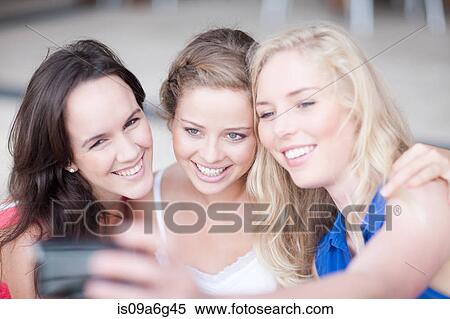Three young women taking photos and showing them to each other View Large Photo Image Stock Photography - Three young women taking photos and showing them to each other. Fotosearch