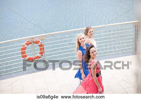 Stock Image - Three young women walking along promenade. Fotosearch