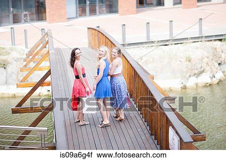 Stock Image - Three young women walking over bridge. Fotosearch