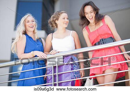 Stock Image - Three young women with shopping bags. Fotosearch