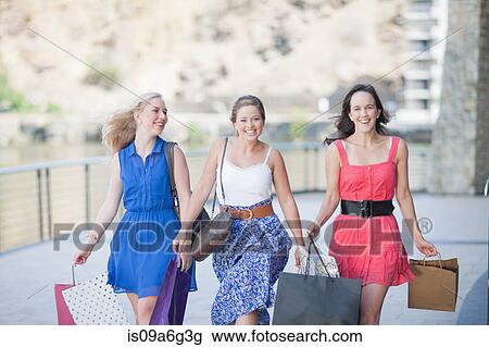 Stock Image - Three young women with shopping bags. Fotosearch
