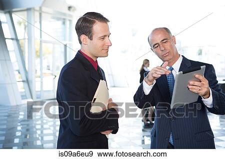 Stock Photo - Two businessmen using digital tablet. Fotosearch
