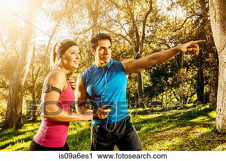 Stock Image - Two people exercising in forest deciding on direction. Fotosearch