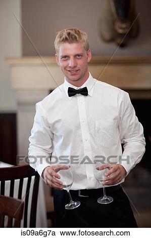 Stock Image - Waiter holding empty wine glasses in restaurant. Fotosearch