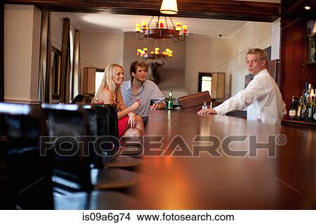 Waiter serving young couple in bar View Large Photo Image Picture - Waiter serving young couple in bar. Fotosearch