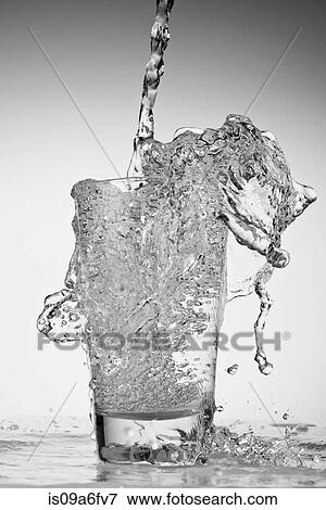 Stock Photo - Water being poured into drinking glass and overflowing. Fotosearch