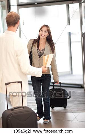 Stock Image - Woman with suitcase and man with airline tickets. Fotosearch