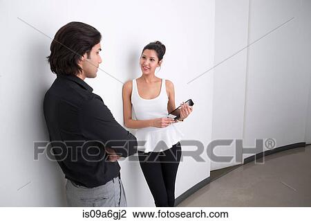 Stock Image - Young businesspeople in corridor talking. Fotosearch