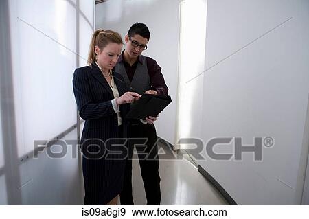 Young businesspeople in corridor using digital tablet View Large Photo Image Stock Photo - Young businesspeople in corridor using digital tablet. Fotosearch