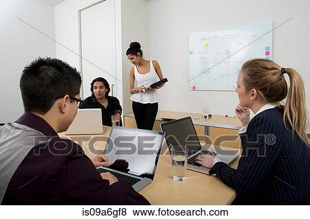 Stock Photo - Young businesspeople using laptops. Fotosearch