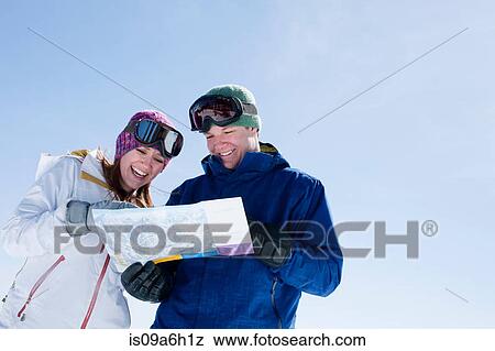 Stock Photo - Young couple holding ski map. Fotosearch