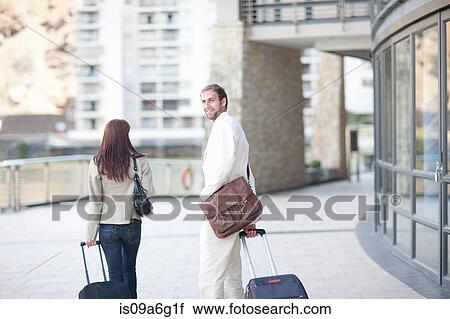 Stock Image - Young man and young woman with suitcases. Fotosearch