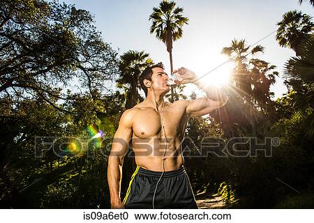 Young man exercising in forest drinking mineral water View Large Photo Image Stock Image - Young man exercising in forest drinking mineral water. Fotosearch