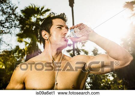 Young man exercising in forest drinking mineral water View Large Photo Image Stock Image - Young man exercising in forest drinking mineral water. Fotosearch