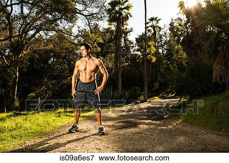 Stock Photo - Young man exercising in forest resting. Fotosearch