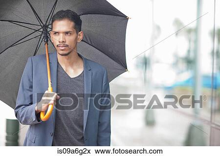 Stock Photo - Young man holding umbrella. Fotosearch