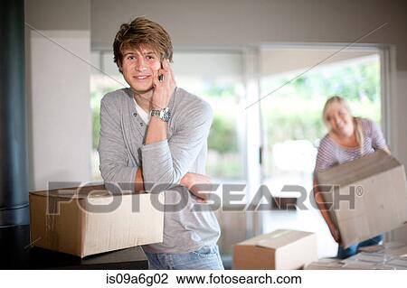 Stock Image - Young man moving house on cell phone. Fotosearch