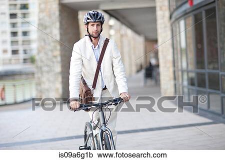 Stock Image - Young man on bicycle wearing helmet. Fotosearch