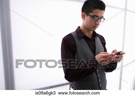 Stock Image - Young man texting on smartphone. Fotosearch