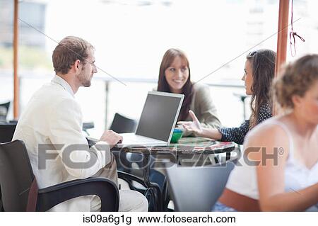 Stock Image - Young man using laptop in cafe. Fotosearch