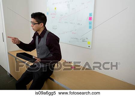 Stock Photography - Young man with whiteboard in background. Fotosearch