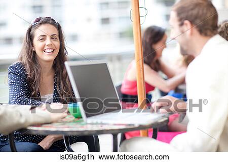 Stock Image - Young woman and young man using laptop in cafe. Fotosearch