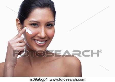 Picture - Young woman applying face cream. Fotosearch