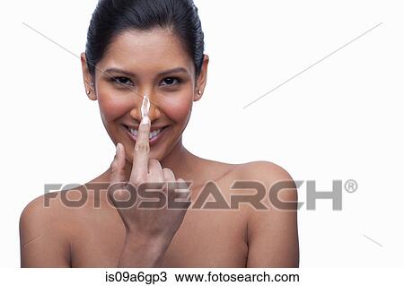 Stock Image - Young woman applying face cream. Fotosearch