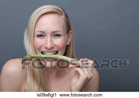 Stock Image - Young woman biting asparagus. Fotosearch